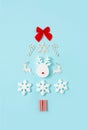 Christmas tree made with snowflake, ribbon, dear horns and candies on bright pastel blue background. Flat lay. Copy space. Minimal Royalty Free Stock Photo