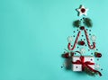 Christmas tree is made of white snowflakes and fir branches, caramel canes, gift box, red stars, balls and bells on a light blue b Royalty Free Stock Photo