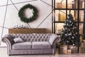 Christmas tree in modern white living room with coach, candles and wreath Royalty Free Stock Photo
