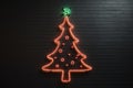 Christmas tree neon illuminated light on a dark wall