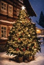 Christmas tree with new year holiday decoration in a city street at night, houses with lights, winter, snow