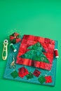 Christmas tree patchwork block, bright square pieces of fabric, pincushion, quilting and sewing accessories on craft mat, green Royalty Free Stock Photo