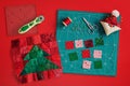 Christmas tree patchwork block, craft mat, bright square pieces of fabric, pincushion like Santa and quilting accessories on red