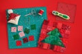 Christmas tree patchwork block, craft mat, bright square pieces of fabric, pincushion like Santa and quilting accessories on red Royalty Free Stock Photo