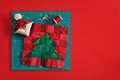 Christmas tree patchwork block, pincushion like Santa, scissors, spool of thread on craft mat, red background Royalty Free Stock Photo