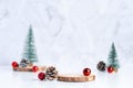 Christmas tree with pine cone and decor xmas ball and empty wood log plate on white table and marble tile wall background.clean Royalty Free Stock Photo