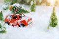 Christmas tree on red car toy with blurred tree background and snow