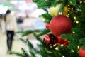 Christmas tree with red toy balls in a shopping mall on festive lights and walking people background Royalty Free Stock Photo