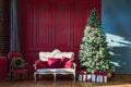 Christmas tree in royal interior. New Year`s Living Room with antique stylish white sofa with luxurious golden accessories. Gifts