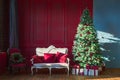 Christmas tree in royal interior. New Year`s Living Room with antique stylish white sofa with luxurious golden accessories. Gifts Royalty Free Stock Photo