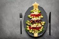 Christmas tree shape appetizers board: cheese, olives, brussels sprout, beef cold cuts, toast bread, sage, rosemary. Festive