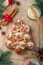 Christmas tree shape cinnamon rolls or cinnabon buns with cinnamon and cream sauce on old tiles background. Festive idea for