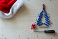 Christmas tree shape with dowels, nuts, screws, screwdriver and gift on a plywood background, Santa`a hat. Cope space, top view