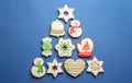 Christmas tree shape made of delicious decorated gingerbread cookies on blue background, flat lay Royalty Free Stock Photo