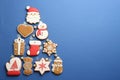 Christmas tree shape made of delicious gingerbread cookies on blue background, flat lay. Space for text Royalty Free Stock Photo