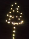 Christmas tree shape shiny lights in darkness. New year tree shape made with led on wall. Royalty Free Stock Photo