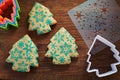 Christmas tree-shaped cookies with snowflakes pattern, stencil, cookie cutters on a wooden cutting board