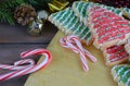 Christmas tree shaped sugar cookies, candy canes pine branches with cones, mini gifts and jingle bells on a wide-plank rustic wood Royalty Free Stock Photo