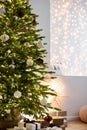 Christmas tree in stylish winter holiday interior with stars, lights, gifts and decoration. Xmas interior design template