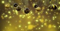 Christmas tree with swinging black and gold baubles over yellow bokeh and light spots, copy space Royalty Free Stock Photo