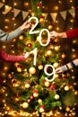 Christmas tree with 2019 text and people hands, new year decoration and lights on wooden background, holiday concept backdrop Royalty Free Stock Photo