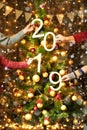 Christmas tree with 2019 text and people hands, new year decoration and lights on wooden background, holiday concept backdrop Royalty Free Stock Photo