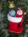 Christmas Tree Toy Santa Claus with a ball of Earth, Golden Bell, Garland, Xmas Red boot against the backdrop of a green artificia Royalty Free Stock Photo