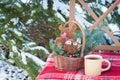 Christmas-tree toys in basket with cup of coffee on wool blanket on the chair near firewood