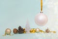 Christmas tree white ball hanging on a gold ribbon on a light blue background with Christmas balls, pine cones and gold Royalty Free Stock Photo