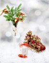 Christmas tree in white decorative goblet, white gift box, red and gold toy bears on sledge, candies and snow