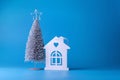 Christmas tree and white wooden house on a blue background. Copy space. Place for text. Christmas, New Year background. Royalty Free Stock Photo