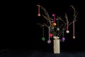 Christmas twig tree table decoration. Colourful baubles and black background.