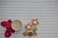 Romantic winter photography image with hot frothy milk drink and luxury chocolates and red rose petals and star shape lit candles