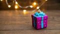 Christmas violet toy for the Christmas tree in the form of a box with a gift stands on an old wooden table, in the background