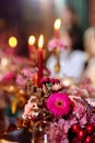 Christmas wedding dinner served table. Shiny leaves of gold paint, pink and red flowers and gold dishes. candles in a metal Royalty Free Stock Photo