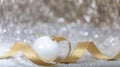 Christmas white ball, golden ribbon and snow, abstract bokeh lights Royalty Free Stock Photo