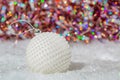 Christmas. White ball nacre pearls on a snow and beautiful blurred colorful background of glittering bokeh with glowing lights. Royalty Free Stock Photo