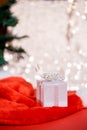 Christmas white gift box with a large bow standing on red hat santa calus against a background bokeh of twinkling golden bokeh