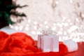 Christmas white gift box with a large bow standing on red hat santa calus against a background bokeh of twinkling golden bokeh