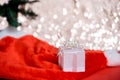 Christmas white gift box with a large bow standing on red hat santa calus against a background bokeh of twinkling golden bokeh