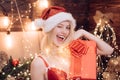 Christmas winking girl posing with red gift box, wink at camera. Woman with a big present in her hands. Smile. Hapiness Royalty Free Stock Photo