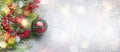 Christmas or winter background with a border of green and frosted evergreen branches, red berries and Christmas bauble on a grey Royalty Free Stock Photo