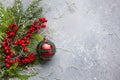 Christmas or winter background with a border of green and frosted evergreen branches, red berries and Christmas bauble on a grey Royalty Free Stock Photo