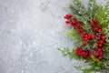 Christmas or winter background with a border of green and frosted evergreen branches and red berries on a grey vintage board. Flat