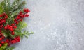 Christmas or winter background with a border of green and frosted evergreen branches and red berries on a grey vintage board. Flat Royalty Free Stock Photo