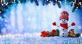 Christmas or winter background with with funny snowman, gift box and fir tree branches in wintery scenery. Fairy holiday card Royalty Free Stock Photo