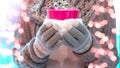 Christmas winter background - Young pretty woman with gloves and scarf stands outdoor and holds a pink hot steaming teacup / cup