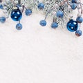 Christmas or winter composition with green Xmas tree twig and blue berries on white snow background Royalty Free Stock Photo