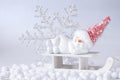 Christmas or winter composition. Young snowman with red woolen cap laying and sleeping on white wooden sledge.