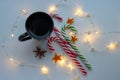 Christmas and winter concept. Black cup of hot coffee, candy cane and garland of white background.Top view. Holiday breakfast Royalty Free Stock Photo